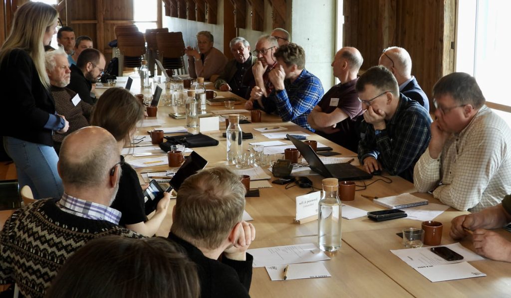Group of people gathered around a table, talking during a workshop.