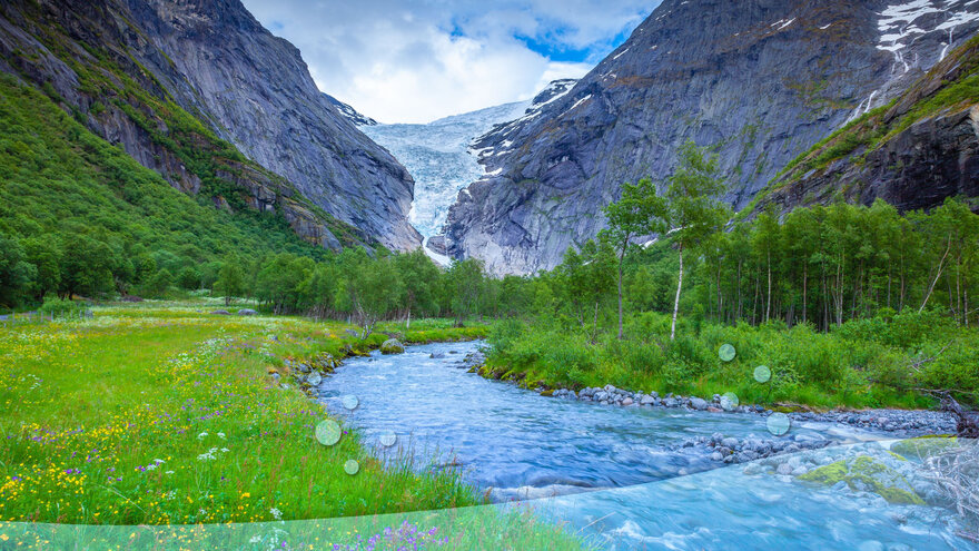 A river flowing between mountains, surrounded by green grass.